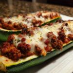 Two baked Zucchini Boats with Ground Turkey & Marinara filling, topped with melted mozzarella cheese.