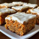 Close-up of a frosted square of Zucchini Carrot Bars recipe, showing shredded carrots and zucchini texture.