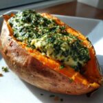 Close-up of a baked sweet potatoes with creamy spinach ricotta filling spooned into the center.