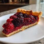 A decadent slice of mixed berry tart, featuring raspberries and blackberries, perfect for a Cookout Spread.