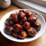 Close-up of roasted Brussels sprouts heavily coated in a thick, dark Sticky Brussels Sprouts Glaze.
