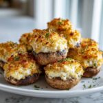 A pile of perfectly baked Crab Stuffed Mushrooms with a golden, crispy topping served on a white plate.