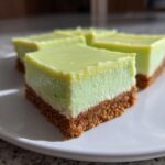 Close-up of several squares of Creamy Key Lime Pie Bars featuring a thick graham cracker crust and bright green filling.