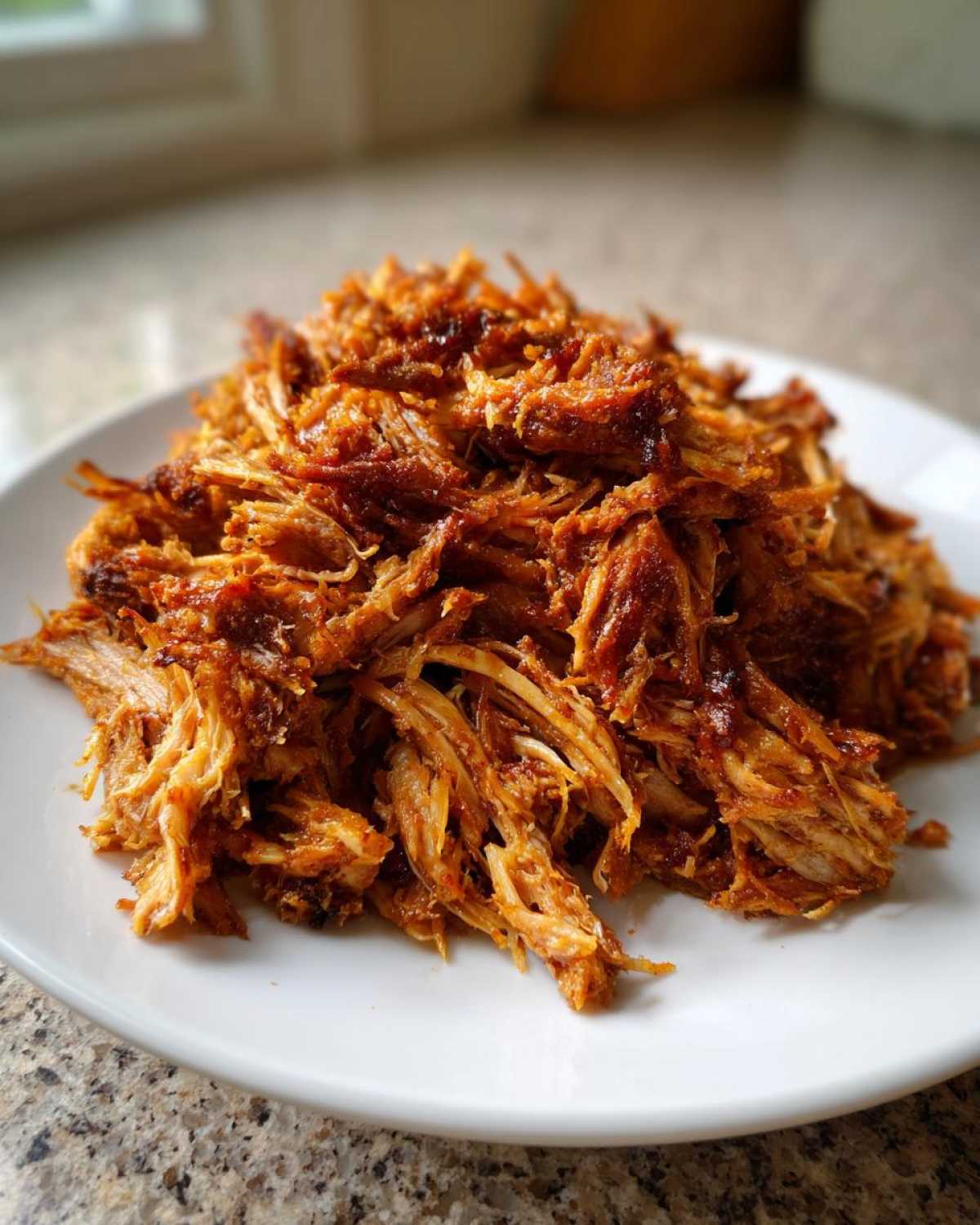 A close-up shot of a generous pile of shredded, caramelized Crispy Slow Cooker Carnitas on a white plate.