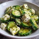 Close-up of a vibrant Cucumber Feta Salad with chunks of feta cheese coated in a bright green Lemon Greek Vinaigrette.