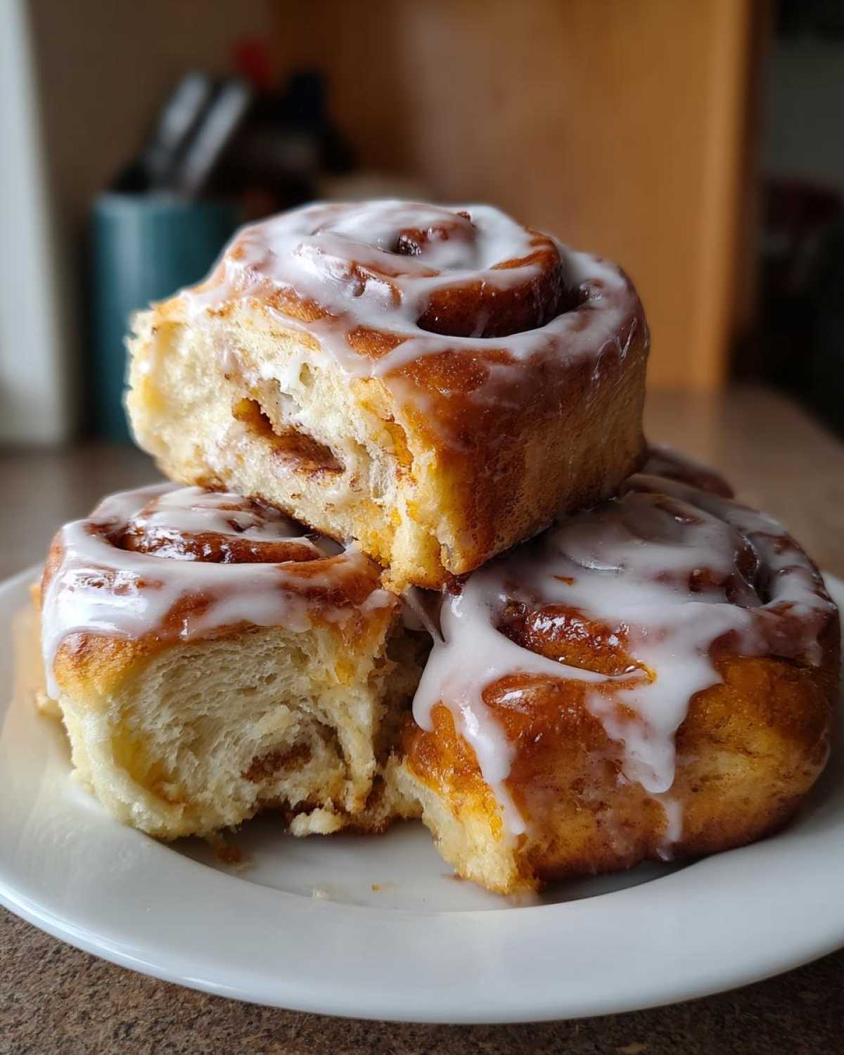 A stack of three fluffy, iced Breakfast Rolls with visible cinnamon swirl and soft interior.