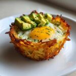A single, crispy Hash Brown Avocado Egg Cup with a sunny-side-up egg and diced avocado on top.