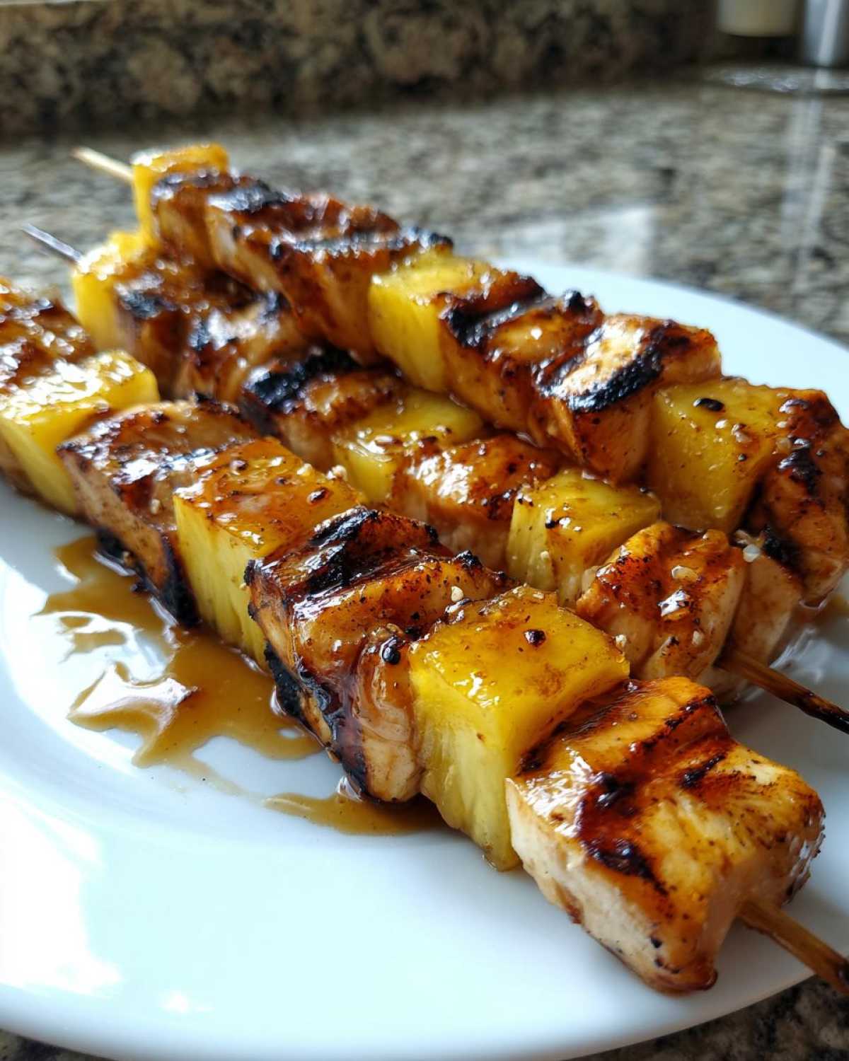Close-up of three grilled Hawaiian Teriyaki Chicken Kabobs Pineapple skewers glistening with sauce on a white plate.