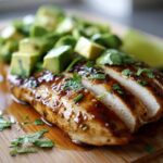Close-up of sliced Honey Lime Chicken Avocado Meal, glazed and topped with diced avocado and cilantro.