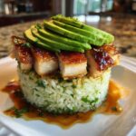 A perfectly plated Honey Lime Chicken and Avocado Rice Stack featuring glazed chicken pieces over cilantro rice, topped with sliced avocado.