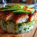 A perfectly formed Honey Lime Chicken and Avocado Rice Stack featuring glazed chicken pieces and sliced avocado on top.