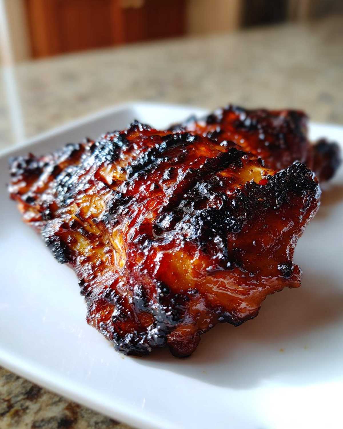 Close-up of a piece of Huli Huli Chicken with a thick, caramelized, and slightly charred glaze.