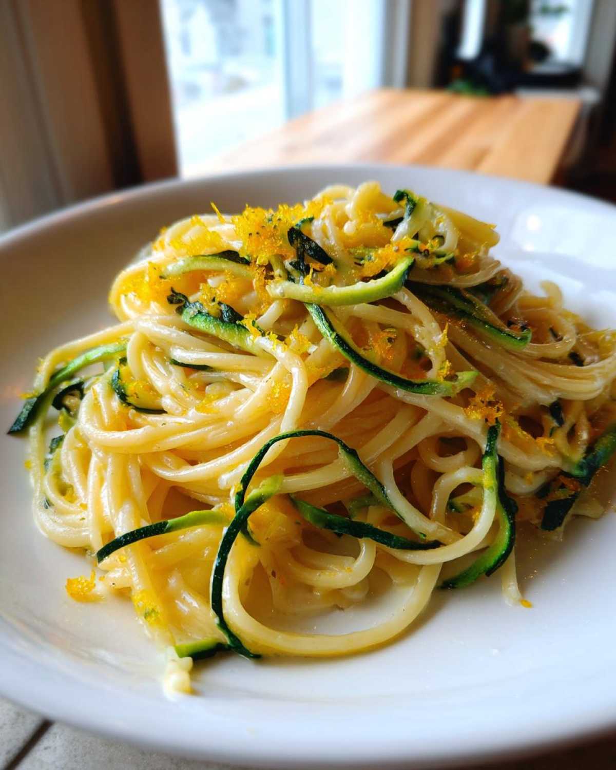 Close-up of creamy Lemon Zucchini Pasta tossed with green zucchini ribbons and bright yellow lemon zest.