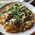 A close-up of a bowl filled with One Pot Chicken Shawarma Rice, topped with yogurt sauce and fresh parsley.