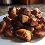 A pile of glossy, caramelized Oven-Roasted Mushrooms with Soy Sauce and Honey served on a white plate.