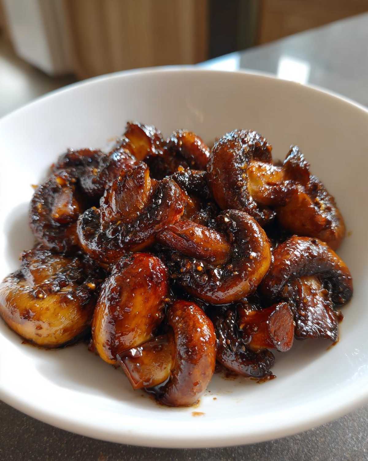 Close-up of glossy, caramelized Oven-Roasted Mushrooms with Soy Sauce and Honey in a white bowl.
