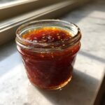 Close-up of homemade Pineapple Jalapeno Bourbon BBQ Sauce stored in a small glass jar.