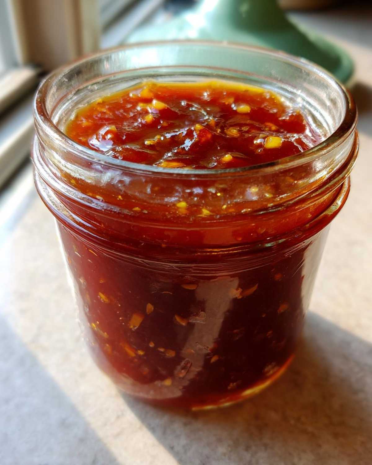 Close-up of a glass jar filled with thick, chunky Pineapple Jalapeno Bourbon BBQ Sauce.