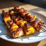 Close-up of grilled Pineapple Teriyaki Chicken Skewers, caramelized and glistening on a white plate.