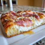 Close-up of a thick slice of Prosciutto Honey Burrata Pizza showing creamy burrata, prosciutto, and honey.