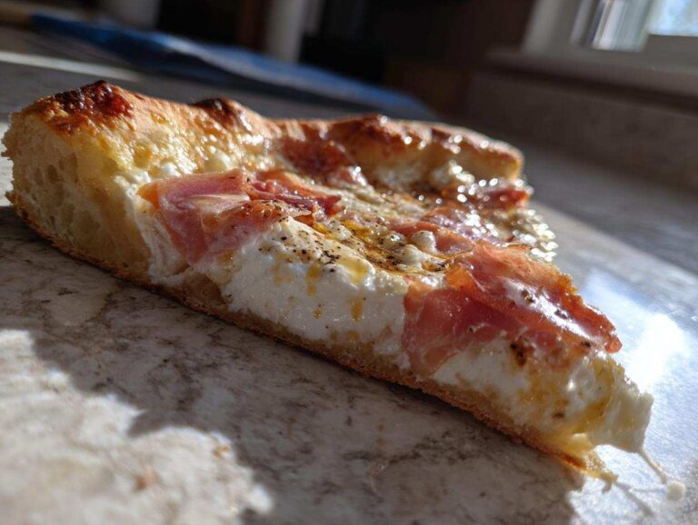 A thick slice of Prosciutto Honey Burrata Pizza showing the fluffy crust, creamy burrata, prosciutto, and honey drizzle.