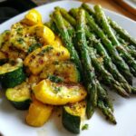 Close-up of roasted asparagus with zucchini and squash, glistening with garlic and herbs.