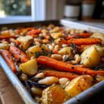 Close-up of Rustic Roasted Vegetable Bake with Cannellini Beans, featuring roasted carrots, potatoes, and herbs on a metal sheet pan.