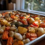 Close-up of a Rustic Roasted Vegetable Bake with Cannellini Beans, featuring caramelized potatoes, carrots, and rosemary on a sheet pan.