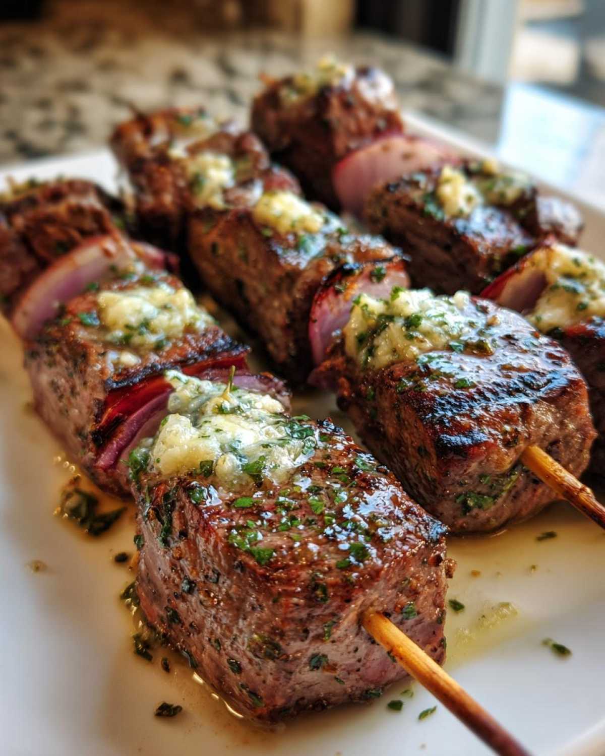 Close-up of grilled steak BBQ skewers topped with melting Cowboy Butter and fresh parsley.