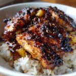 Close-up of caramelized Teriyaki Pineapple Chicken Thighs served over white rice in a bowl.