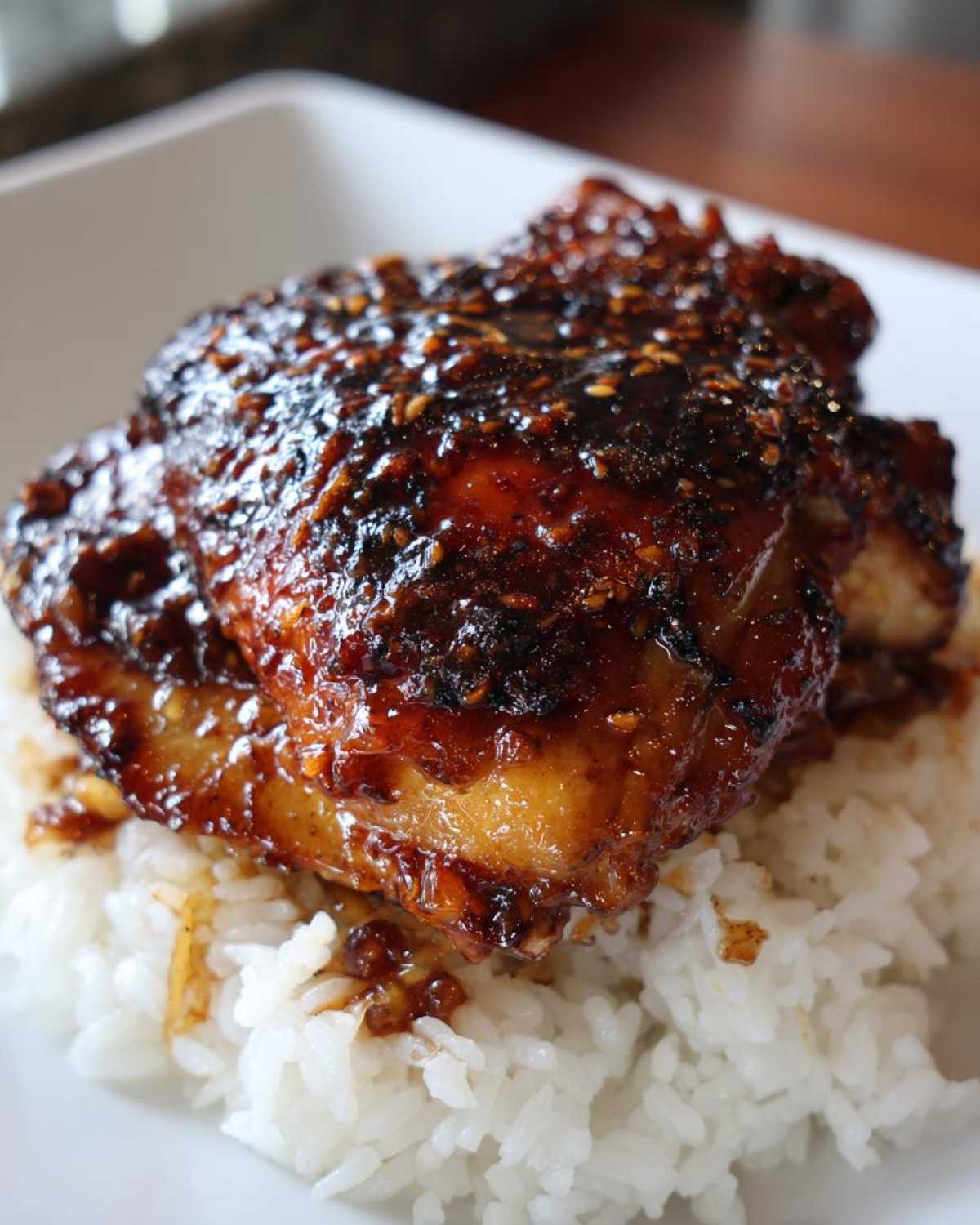 Close-up of a glazed Teriyaki Pineapple Chicken Thighs piece served over white rice, topped with sesame seeds.