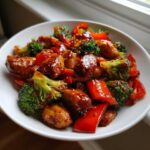 Close-up of Thai Chicken Sweet and Spicy dish featuring glazed chicken pieces, bright red bell peppers, and vibrant green broccoli florets.