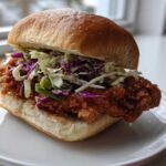 A close-up of a Thai Fried Chicken Sandwich Asian with crispy fried chicken and colorful coleslaw on a soft bun.