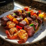 Close-up of perfectly cooked Grilled Steak and Shrimp Skewers with colorful bell peppers, glistening with garlic butter.