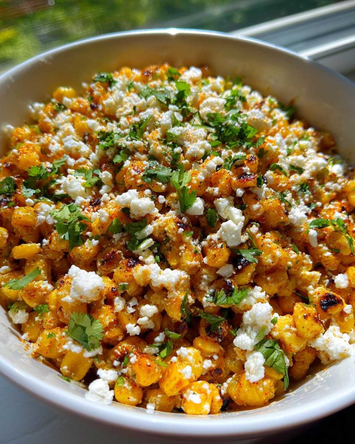 Close-up of vibrant Mexican Street Corn Salad kernels tossed in spices, topped with crumbled white cheese and fresh cilantro.