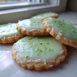 A stack of freshly baked Mojito Sugar Cookies topped with pale green lime icing and bright green zest.