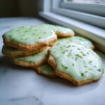 A stack of freshly baked Mojito Sugar Cookies topped with light green icing and bright lime zest.