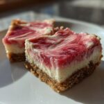 Two decadent squares of No Bake Rhubarb Bars featuring a graham cracker crust and a creamy, pink swirled topping.