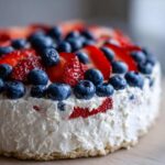 Close-up of the creamy topping of the Red, White & Blue Cheesecake Dip, loaded with fresh blueberries and sliced strawberries.